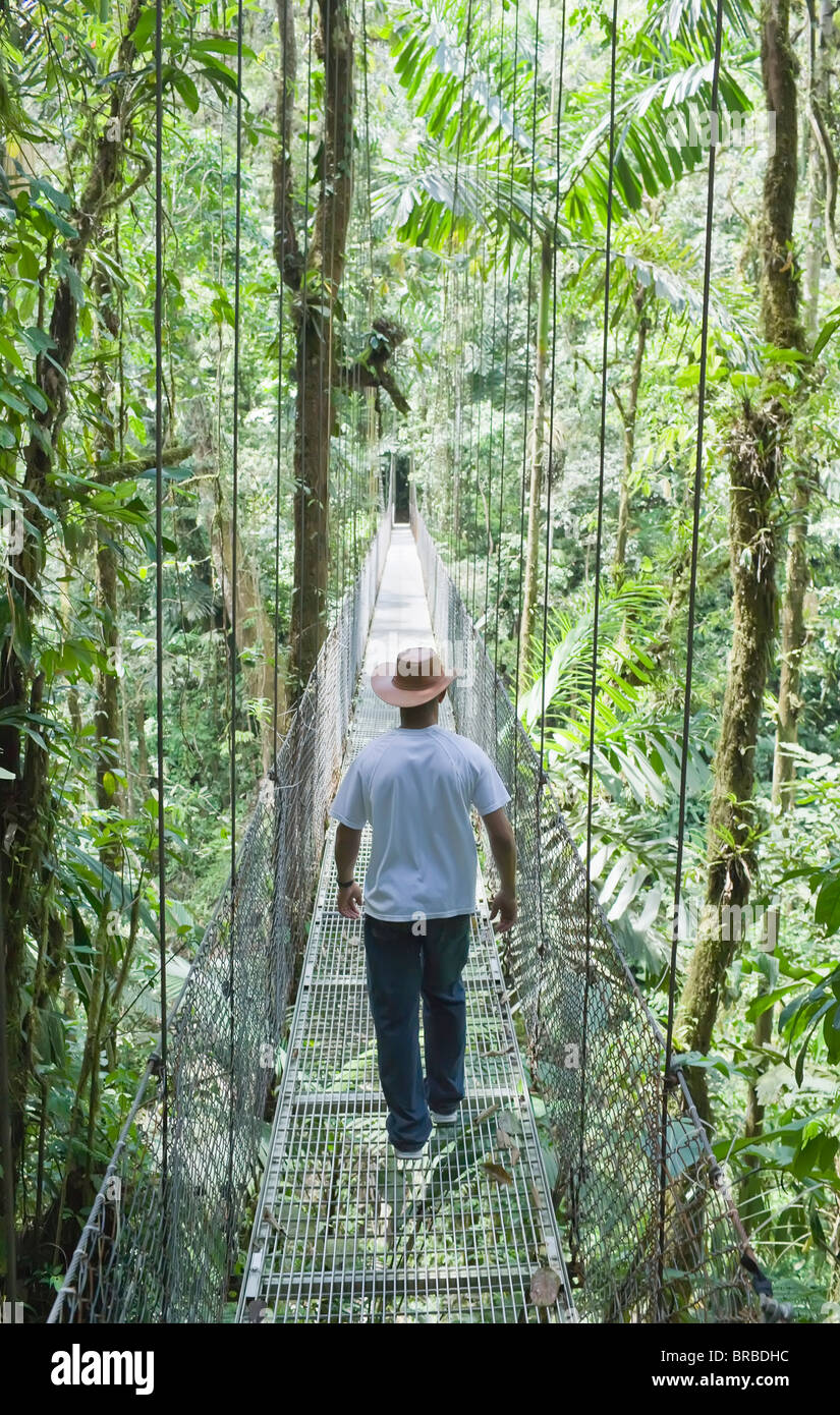 Mann zu Fuß über die Hängebrücke im Regenwald,, La Fortuna, Arenal, Costa Rica, Mittelamerika Stockfoto