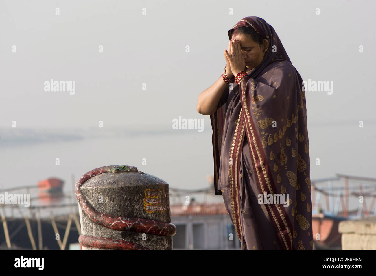 Frau beten vor ein Lingam, Varanasi, Uttar Pradesh, Indien Stockfoto