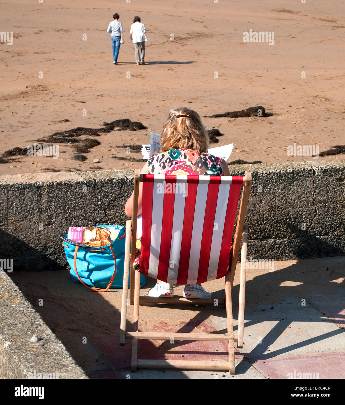 eine junge Frau sitzt in einem Liegestuhl am Summerleaze Beach, Bude, cornwall Stockfoto