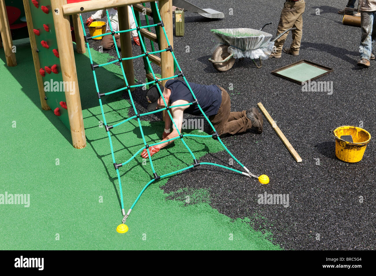 Arbeiter verlegen eine Sicherheit-Oberfläche auf einem Kinderspielplatz im Dorf Dent, Cumbria. Stockfoto
