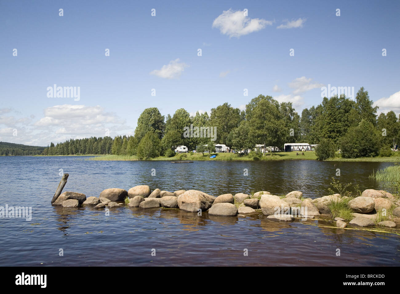 Lake Ovre Brocken in der Nähe von Torsby mit Damm aus Steinen und Campingplatz im Hintergrund, Värmland, Schweden Stockfoto