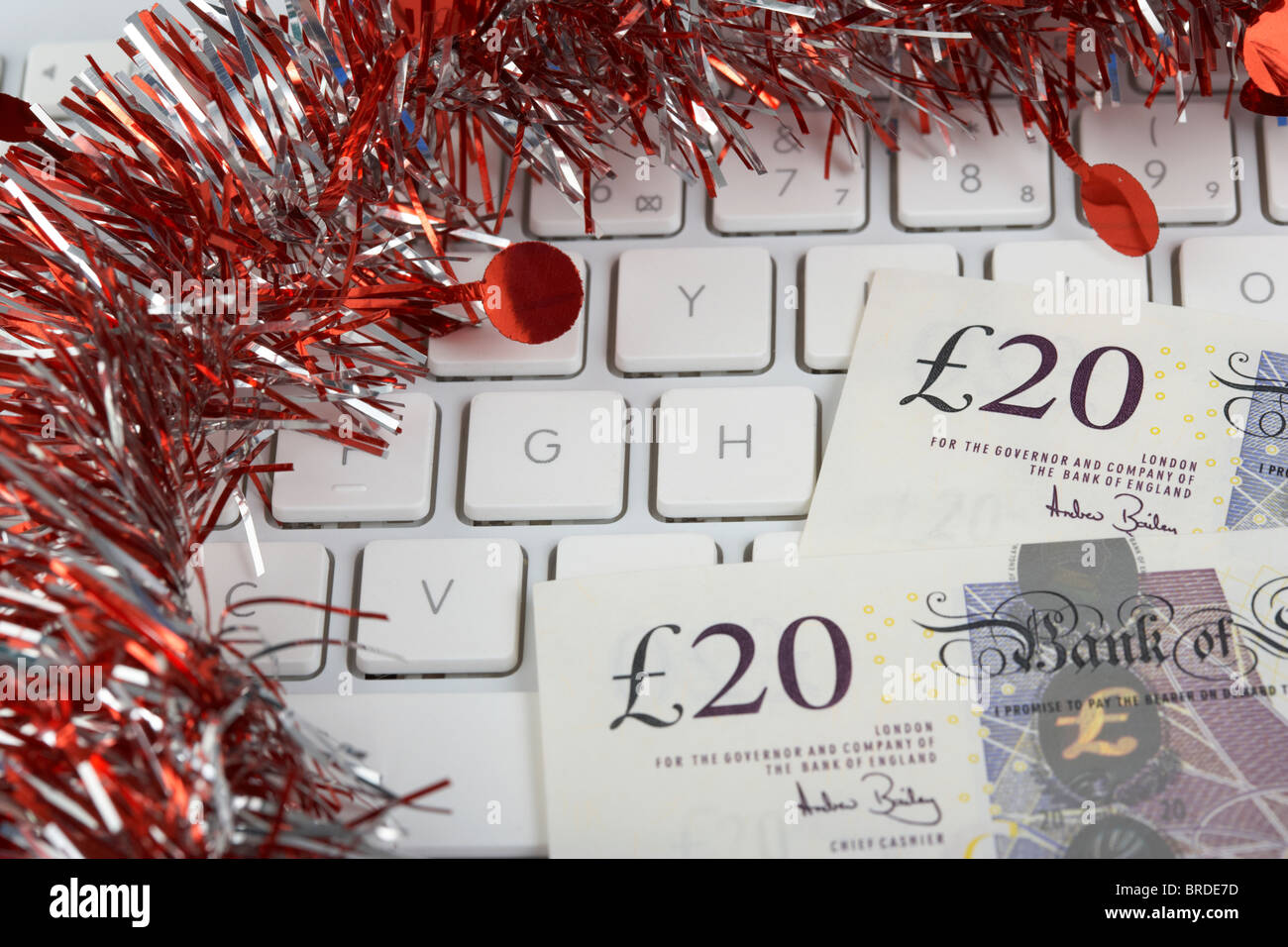 Haufen von zwanzig Pfund Sterling Banknoten auf einer Computertastatur mit Lametta Weihnachtsdekoration Stockfoto