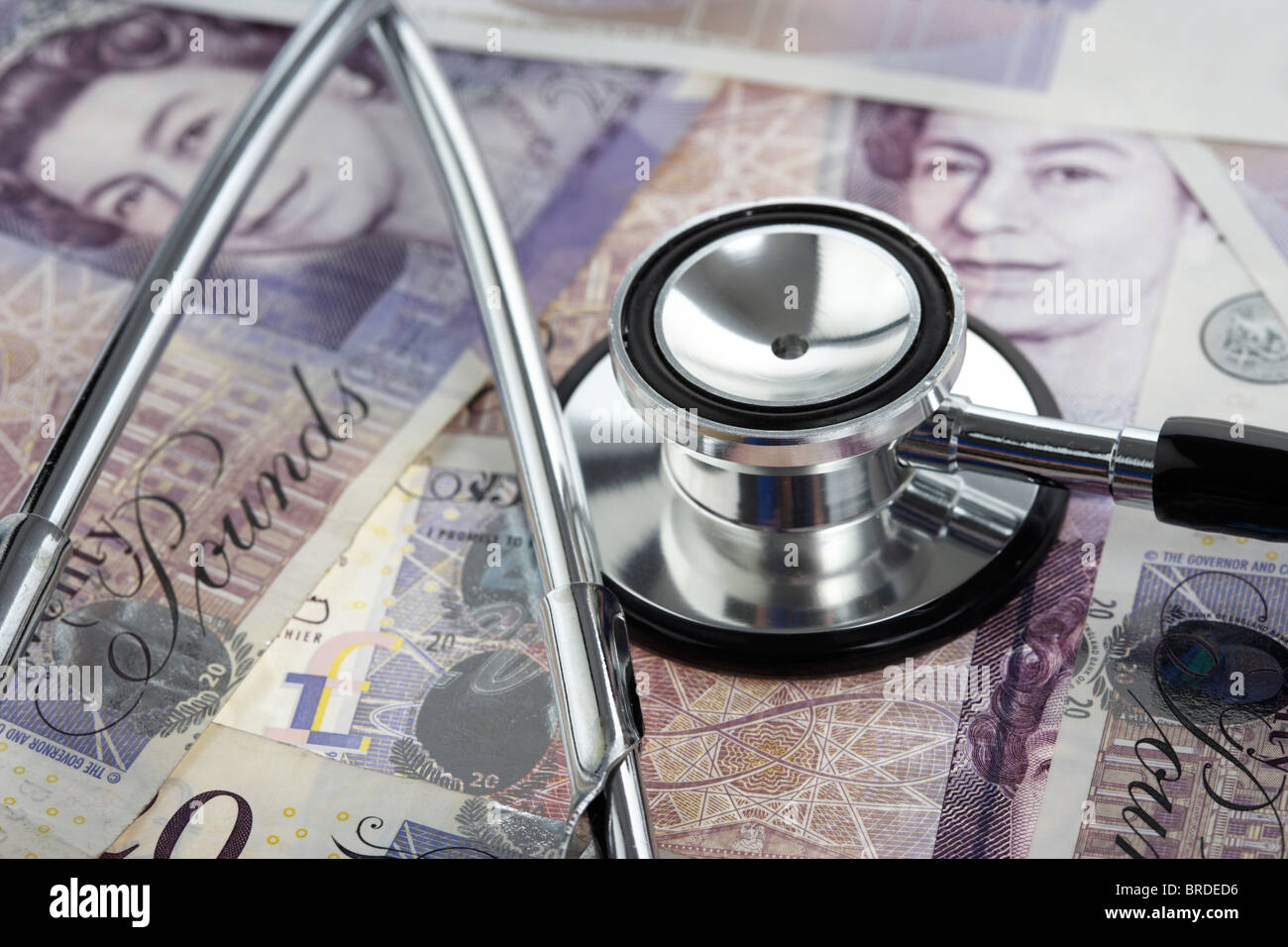medizinische Stethoskop auf einen Haufen von zwanzig Pfund Sterling Banknoten Stockfoto