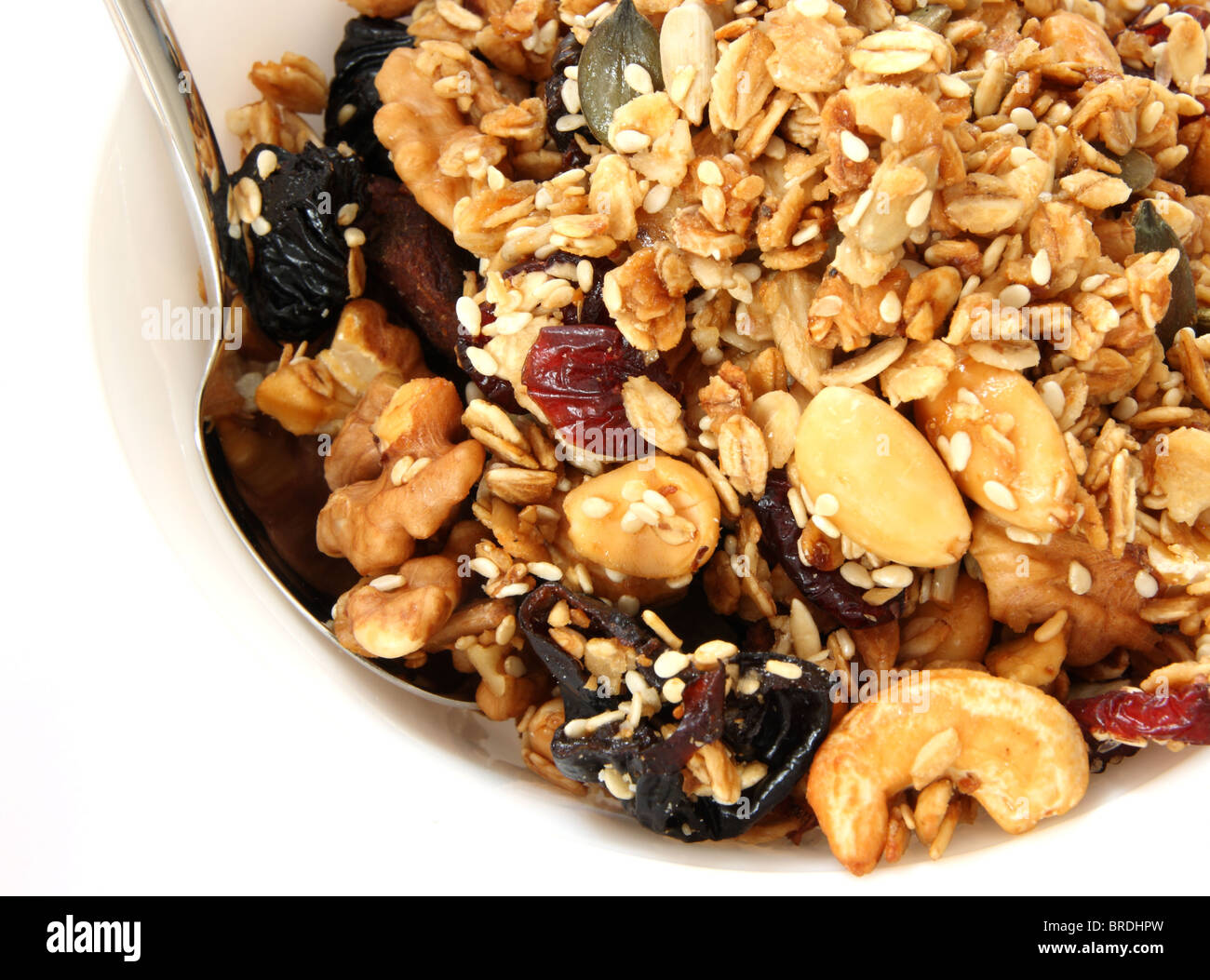 Gebackene Müsli in weiße Schüssel mit Früchten und Nüssen auf weißem Hintergrund mit einem Löffel Stockfoto