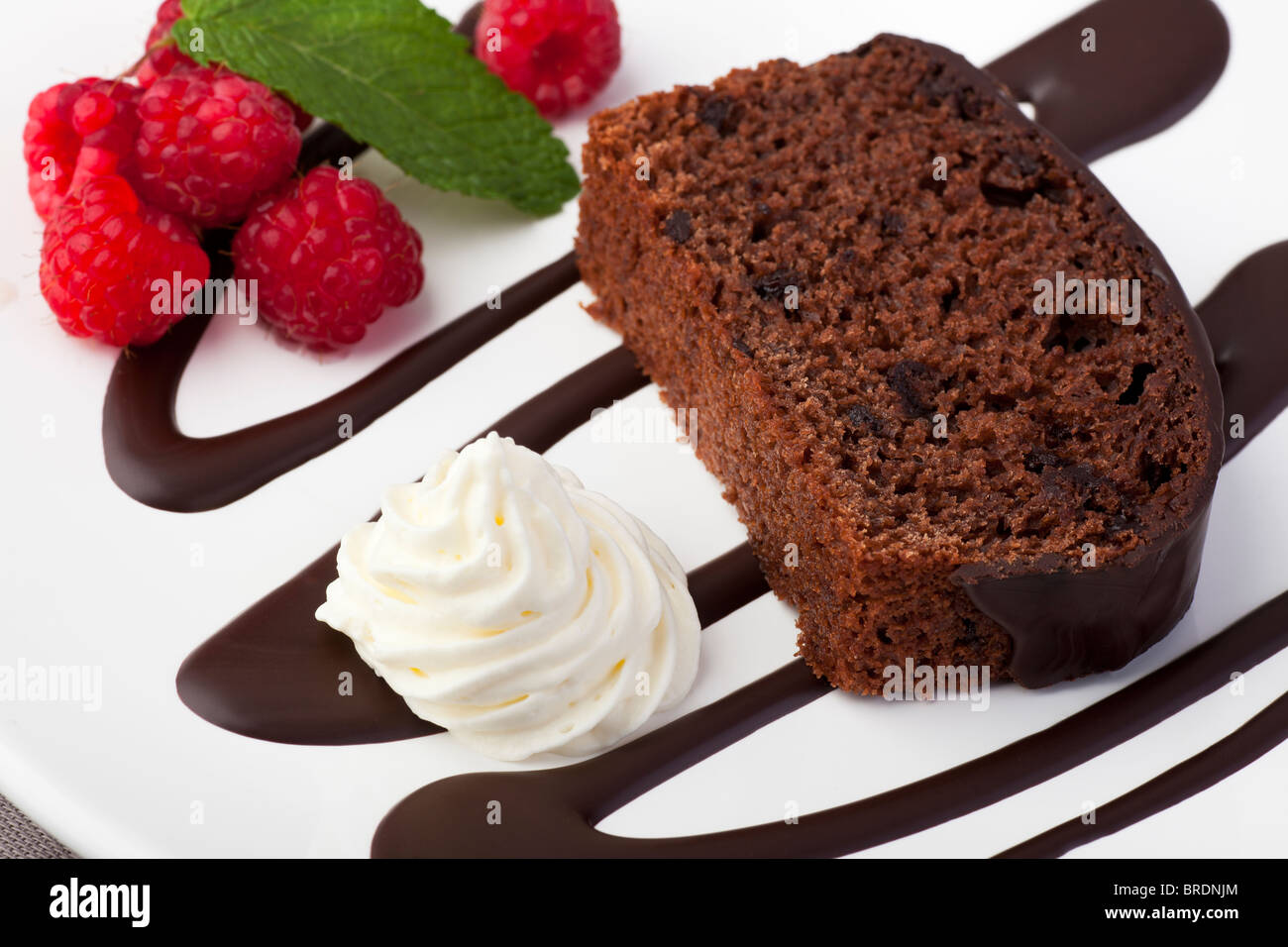 Frische Schokoladenkuchen mit Himbeeren und Sahne. Stockfoto