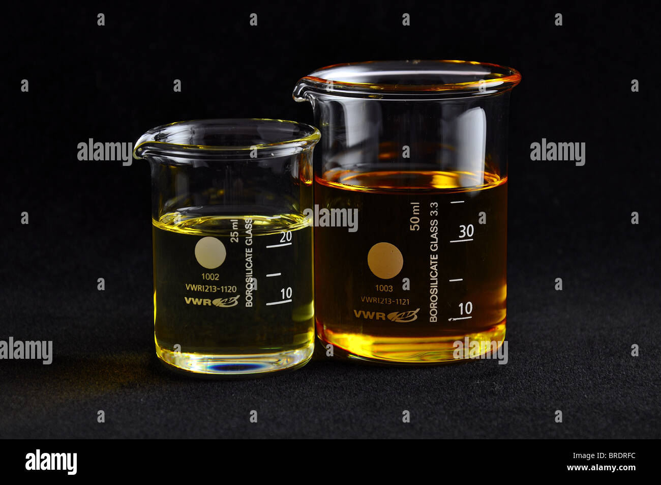 Farbloses Glas Becher messen 25ml und 50ml Trägeröl mit schwarzen nahtlose Hintergrund Öle. weiche seitliche Beleuchtung Stockfoto