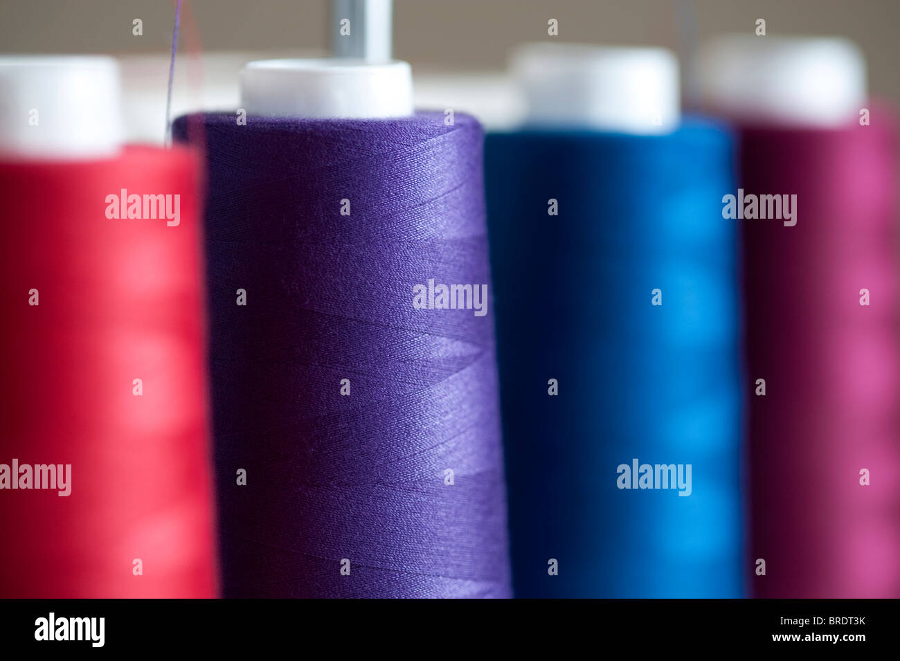 Bunte Spulen des Threads auf einer Spindel auf einer Nähmaschine serger Stockfoto