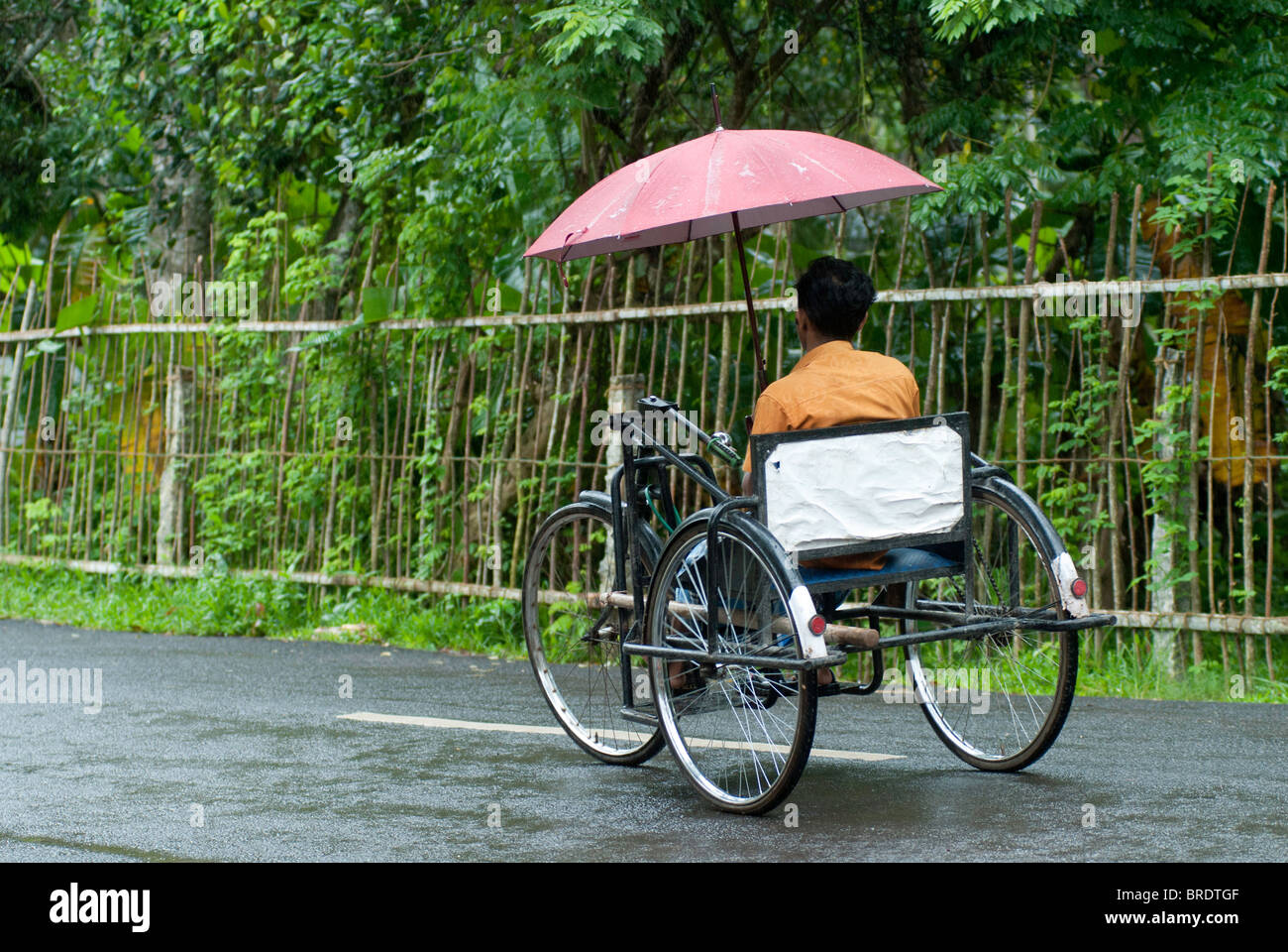 Behinderten Mann Reiten ein Dreirad während einer regnerischen; Monsun-Tag am Allappuzha; Alleppey, Kerala. Stockfoto