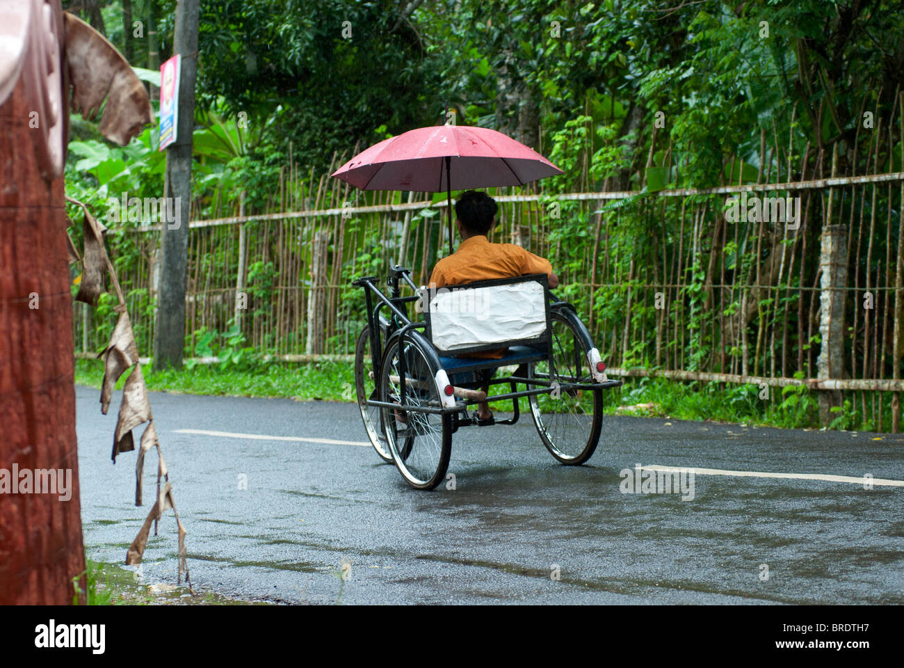 Behinderten Mann Reiten ein Dreirad während einer regnerischen; Monsun-Tag am Allappuzha; Alleppey, Kerala. Stockfoto