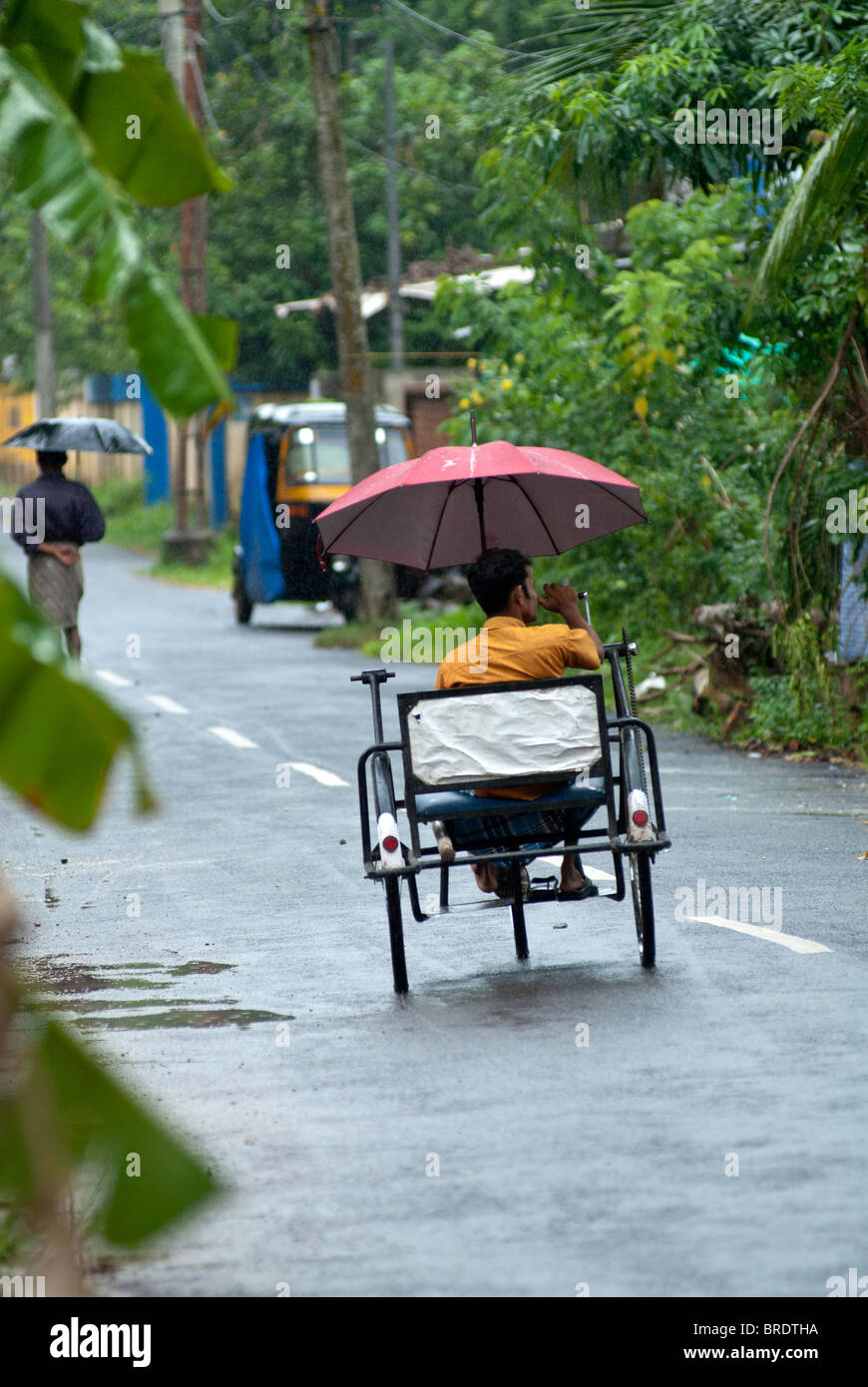 Behinderten Mann Reiten ein Dreirad während einer regnerischen; Monsun-Tag am Allappuzha; Alleppey, Kerala. Stockfoto