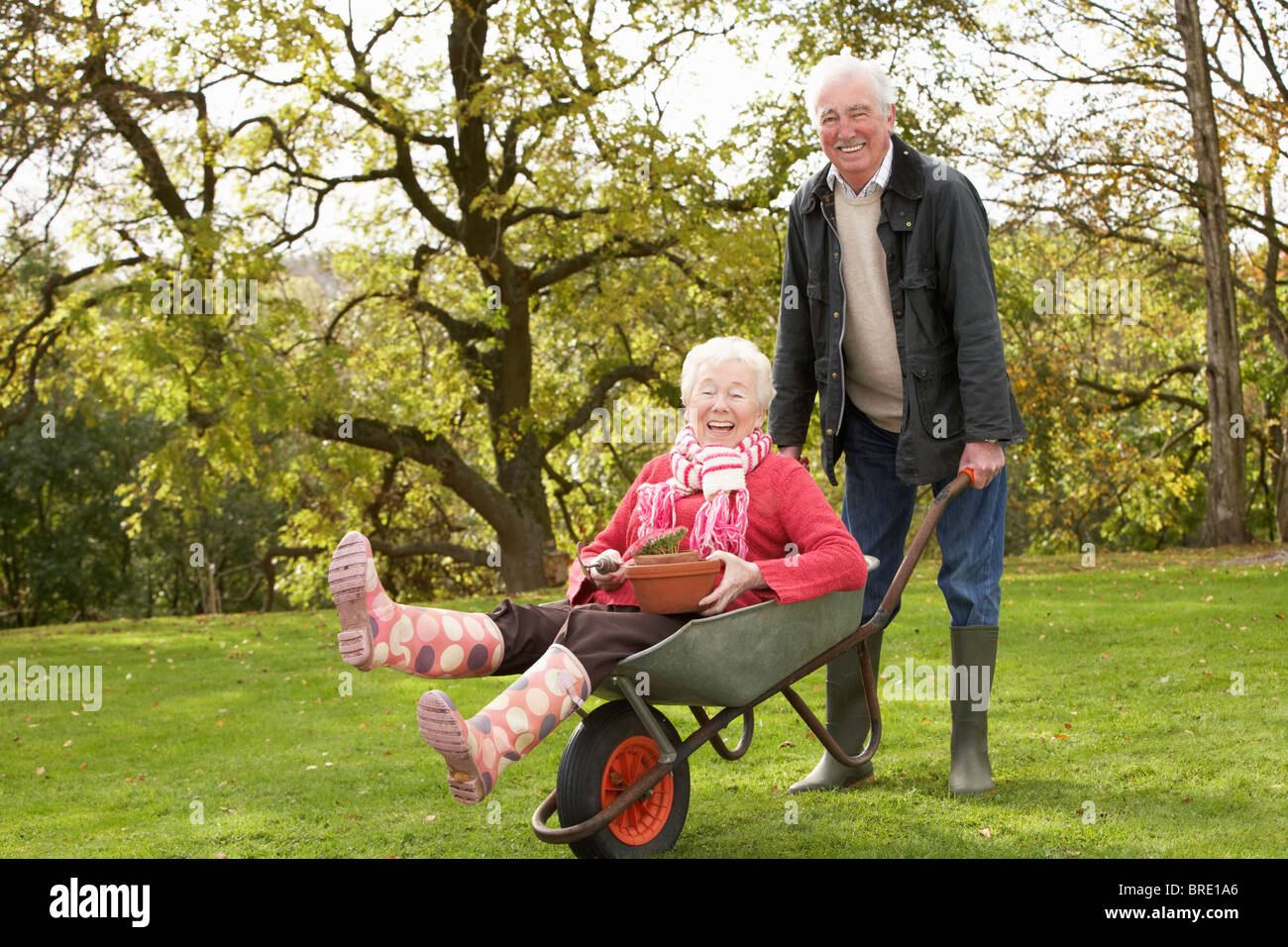 Älteres paar Mann geben Frau Fahrt In Schubkarre Stockfoto
