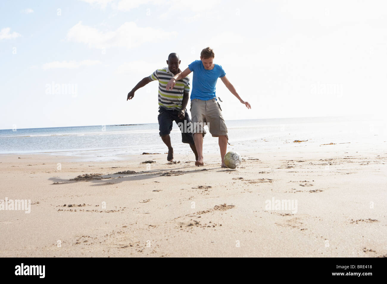 Zwei junge Männer Palying Fußball am Strand zusammen Stockfoto