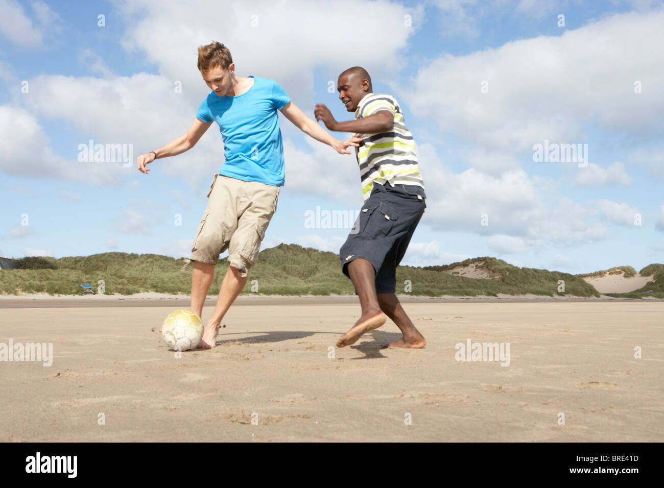 Zwei junge Männer Palying Fußball am Strand zusammen Stockfoto