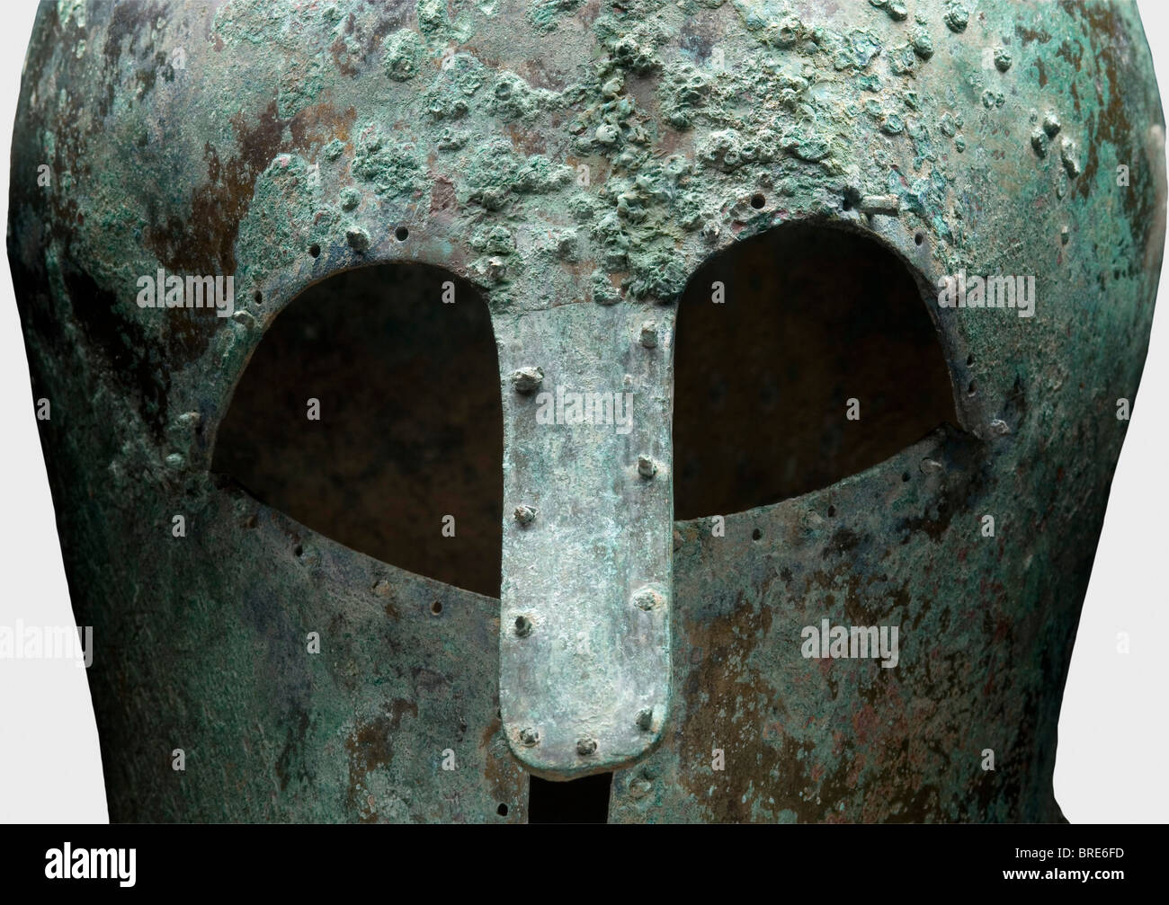 Ein korinthischer Helm, 7./6. Jahrhundert v. Chr. Dickwandiger, schwerer korinthischer Bronze-Helm mit hohem Schädel und verlängertem Nackenschutz. Große Augenausschnitte, leicht konkave Wangenstücke und ein robuster, genieteter langer Nasenschutz, der nach außen gebogen ist. Umgeben von gebohrten Löchern, einige paarweise, und einige halten noch die dekorativen oder auskleidung Nieten mit runden Köpfen. Höhe 22,1 cm. Gewicht 1288 g Metalloberflächen mit hellbrauner, dunkler und hellgrüner Patina. Schmutzrückstände im Inneren. Isolierte Korrosionsgruben an der Oberfläche. Sehr gute Metallrückhaltung. Sammlung Axel Guttmann (H 147/ A, Stockfoto