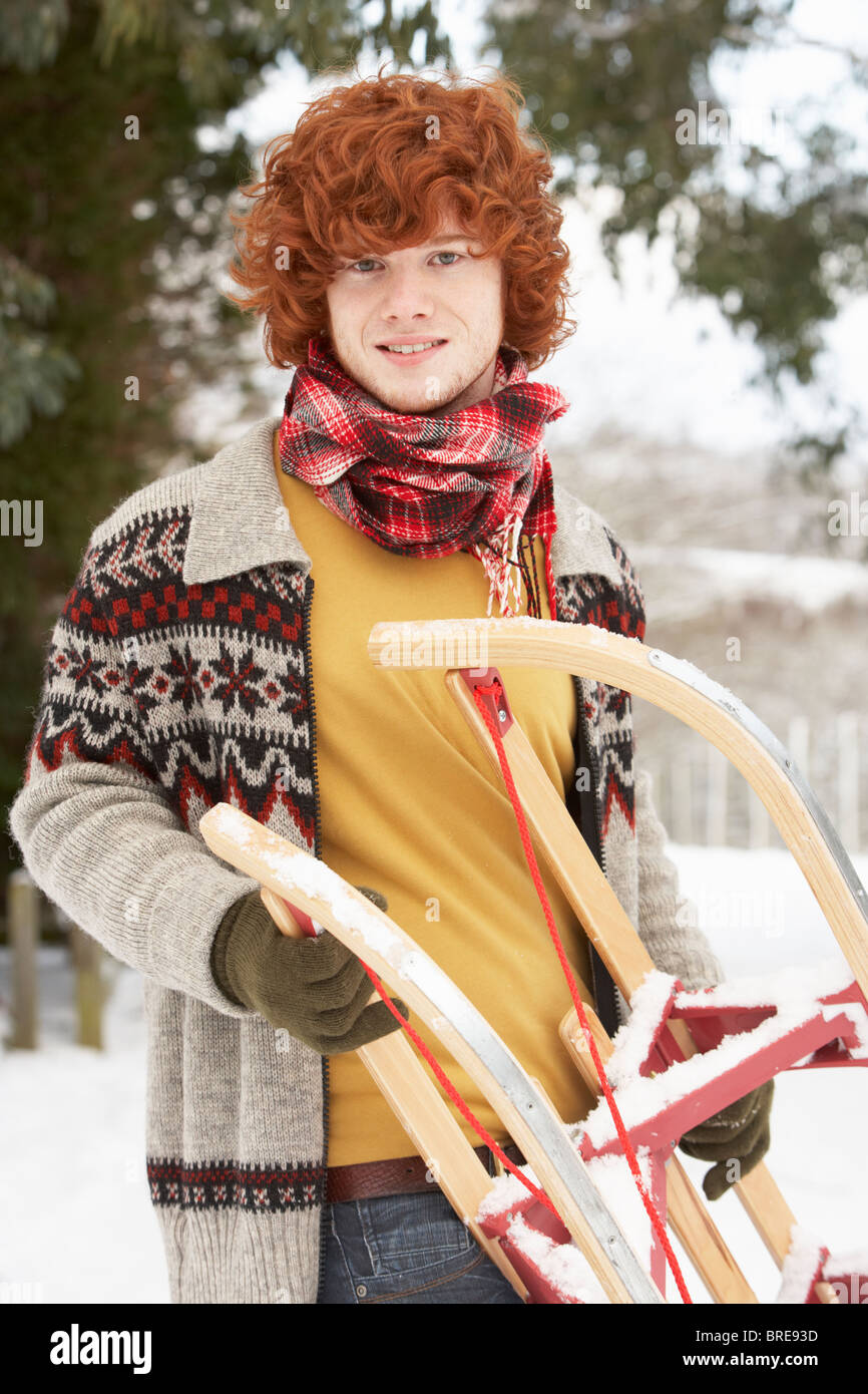 Teenager mit Schlitten In Schneelandschaft Stockfoto