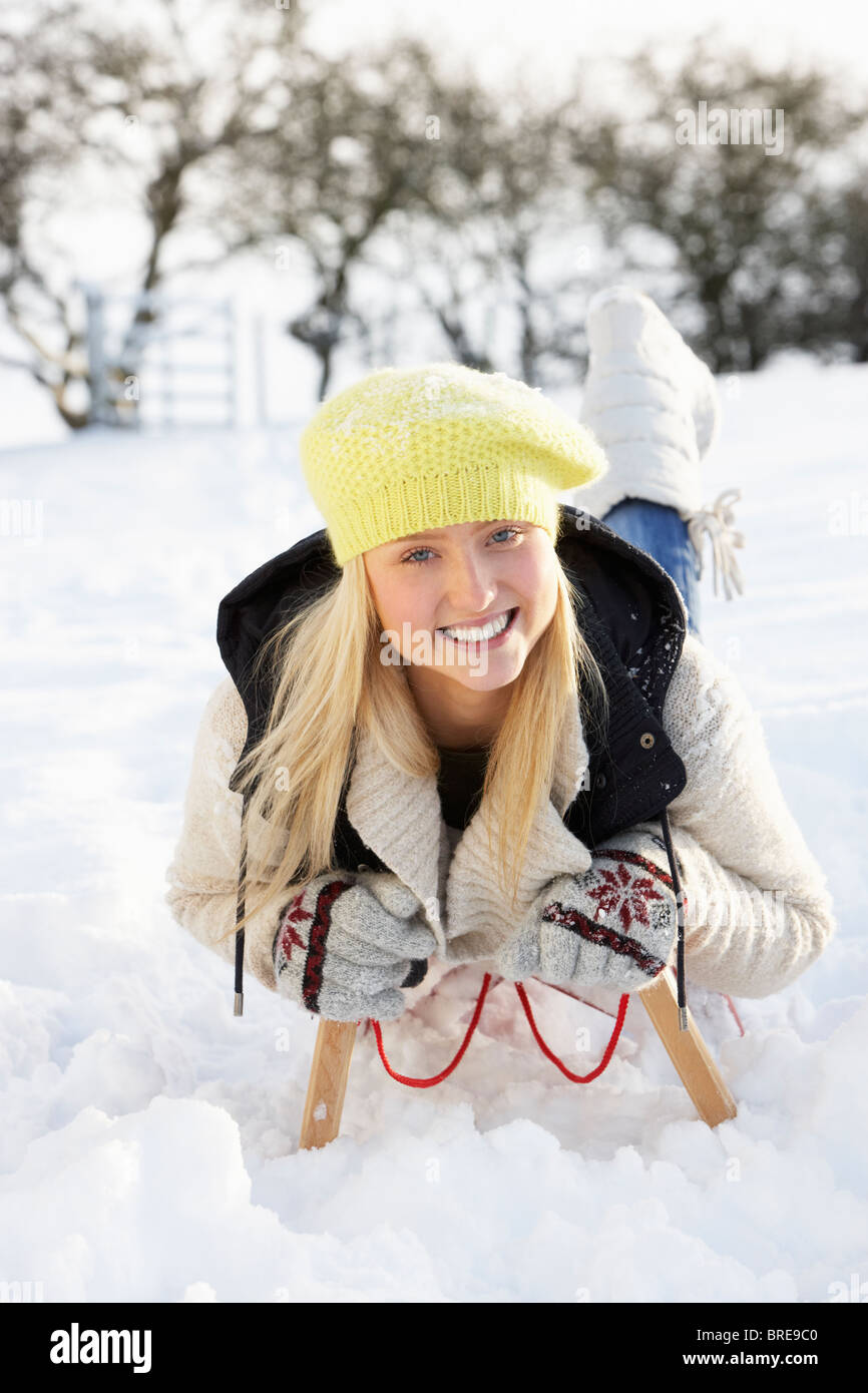Teenager-Mädchen reiten auf Schlitten In Schneelandschaft Stockfoto
