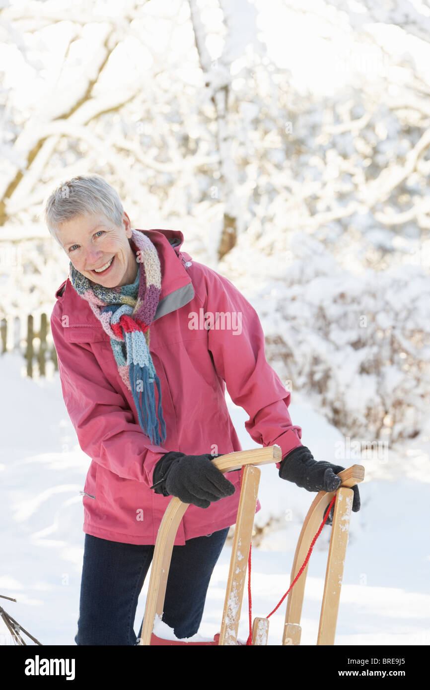 Ältere Frau mit Schlitten In verschneiter Landschaft Stockfoto