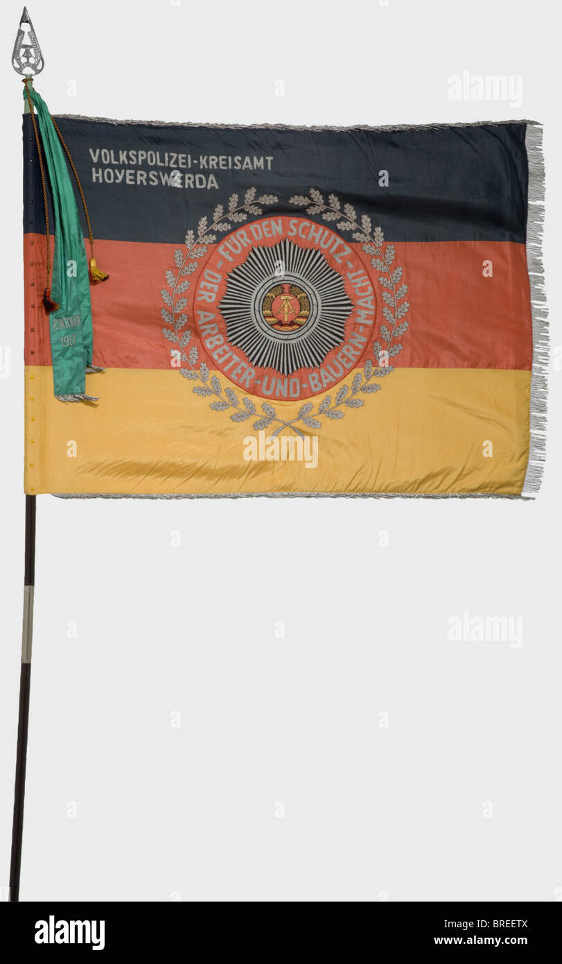 Ein Banner für das "Volkspolizei-Kreisamt Hoyerswerda" (Bezirksamt Hoyerswerda Volkspolizei), mit allem Zubehör und der Verleihungsurkunde Seide mit einem silbernen Fransen auf drei Seiten, beide Seiten horizontal in schwarz-rot-Gold geteilt mit einem farbigen Wappen in der Mitte, umgeben von der silberbestickten Aufschrift, "Für den Schutz der Arbeiter- und Bauernmacht" (Zum Schutz der Arbeiter- und Bauernmacht) und einen Eichenblattkranz. Auf der obversen Seite eine entsprechende silberbestickte Aufschrift in der linken oberen Ecke. Abmessungen 155 x 1, Stockfoto