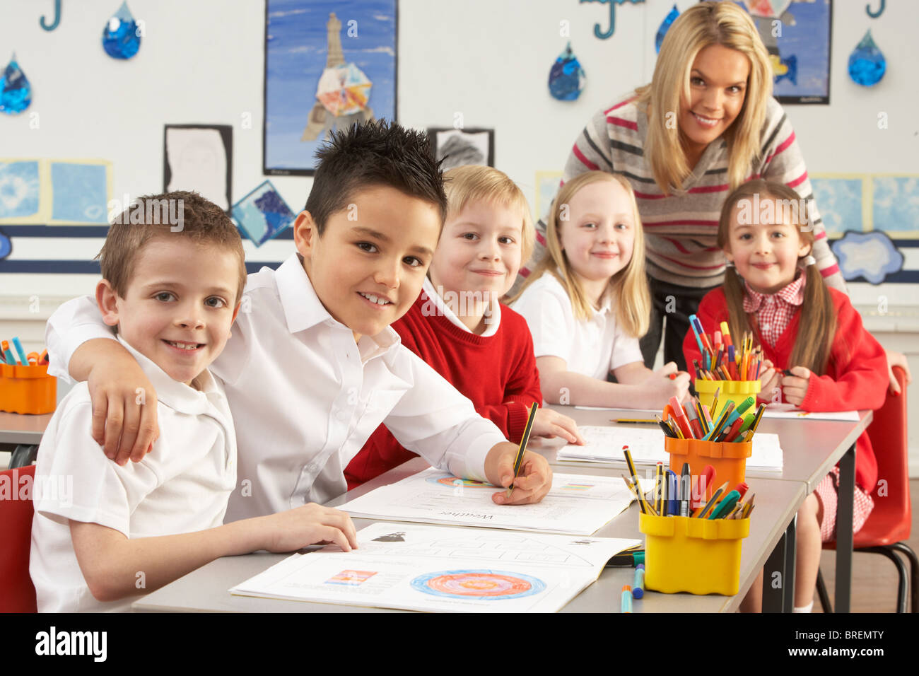Gruppe der Grundschulkinder und Lehrer arbeiten am Schreibtisch im Klassenzimmer Stockfoto