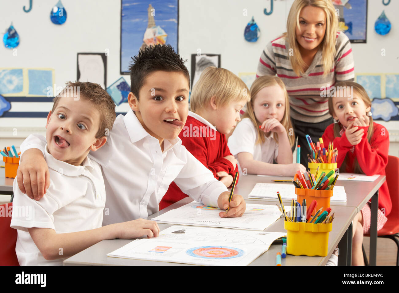 Gruppe der Grundschulkinder und Lehrer arbeiten am Schreibtisch im Klassenzimmer Stockfoto