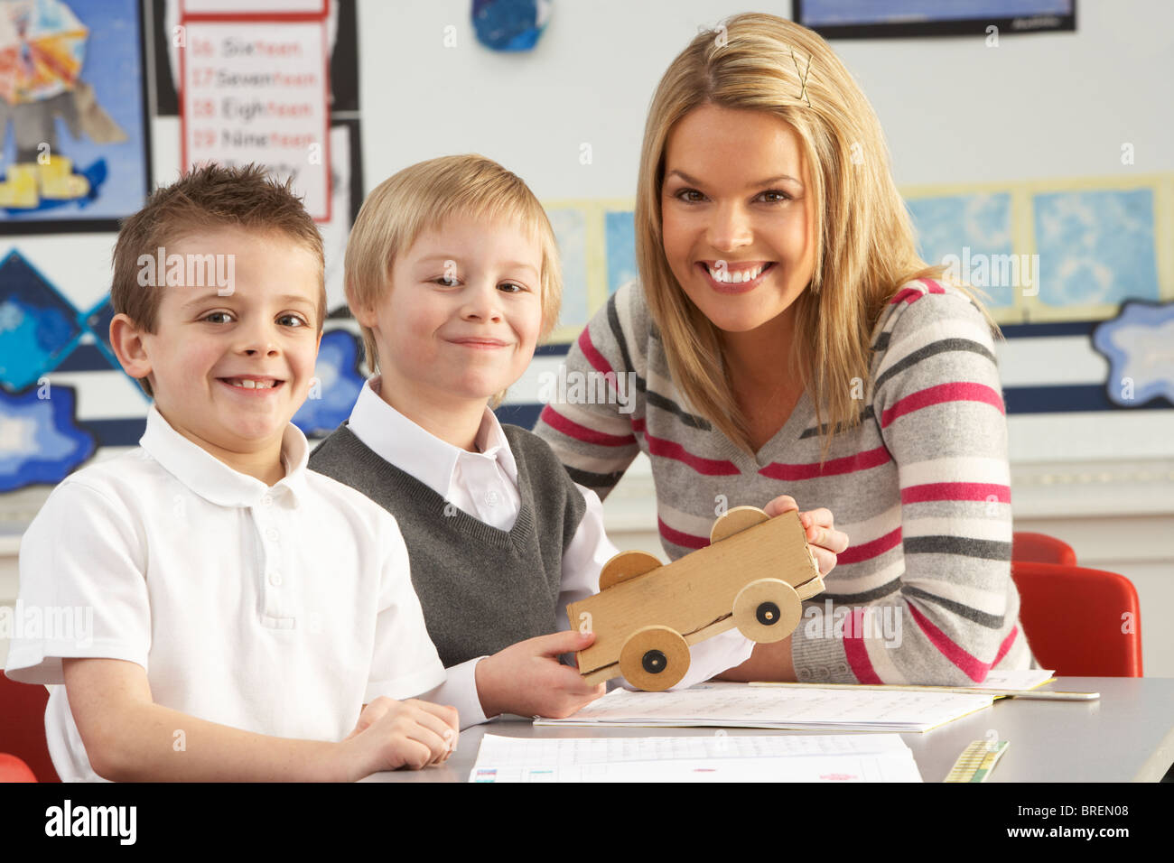 Zwei männliche Grundschüler und Lehrer arbeiten am Schreibtisch im Klassenzimmer Stockfoto
