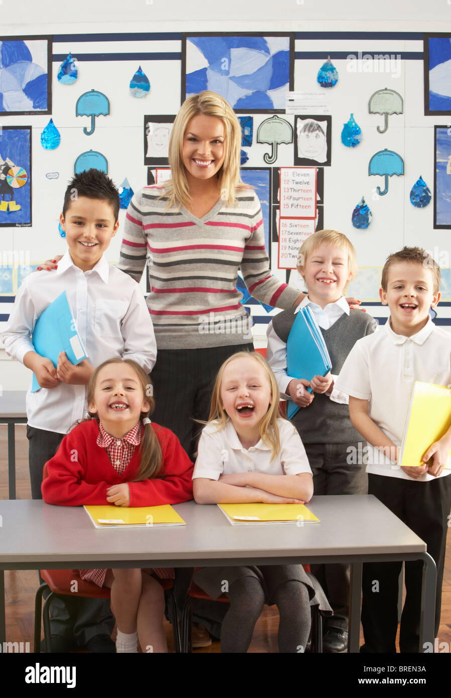 Porträt der Gruppe der Grundschulkinder und Lehrer sitzen am Schreibtisch im Klassenzimmer Stockfoto