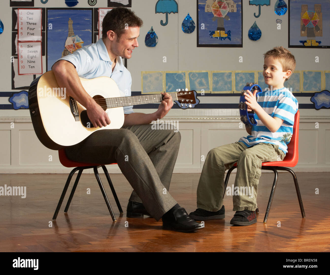 Männliche Lehrer Gitarre mit Schüler im Klassenzimmer Stockfoto