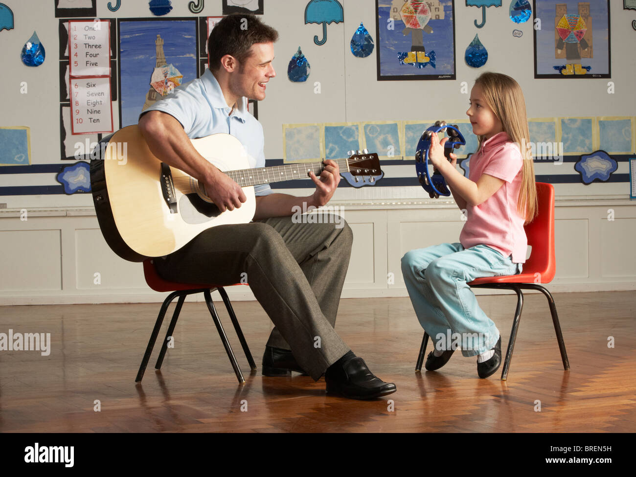 Männliche Lehrer Gitarre mit Schüler im Klassenzimmer Stockfoto