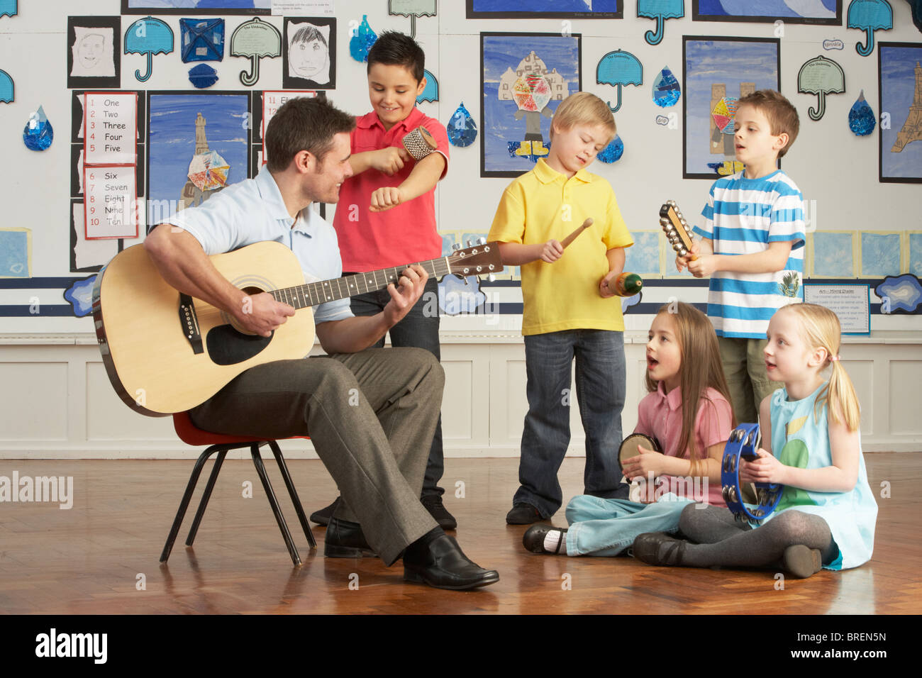 Männliche Lehrer Gitarre mit Schülerinnen und Schülern mit Unterricht im Klassenzimmer Stockfoto
