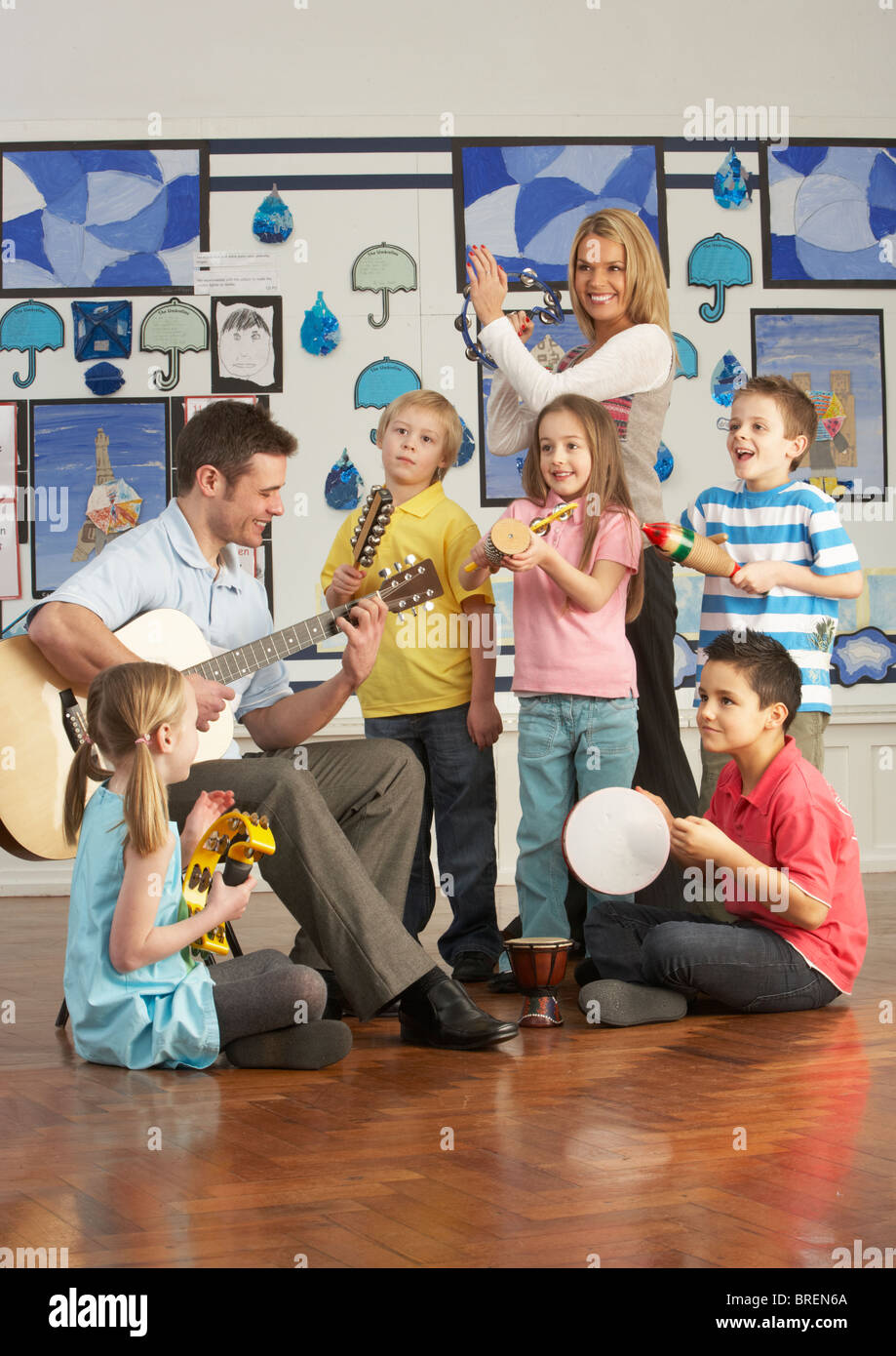 Lehrer spielen Gitarre mit Schülerinnen und Schülern mit Unterricht im Klassenzimmer Stockfoto