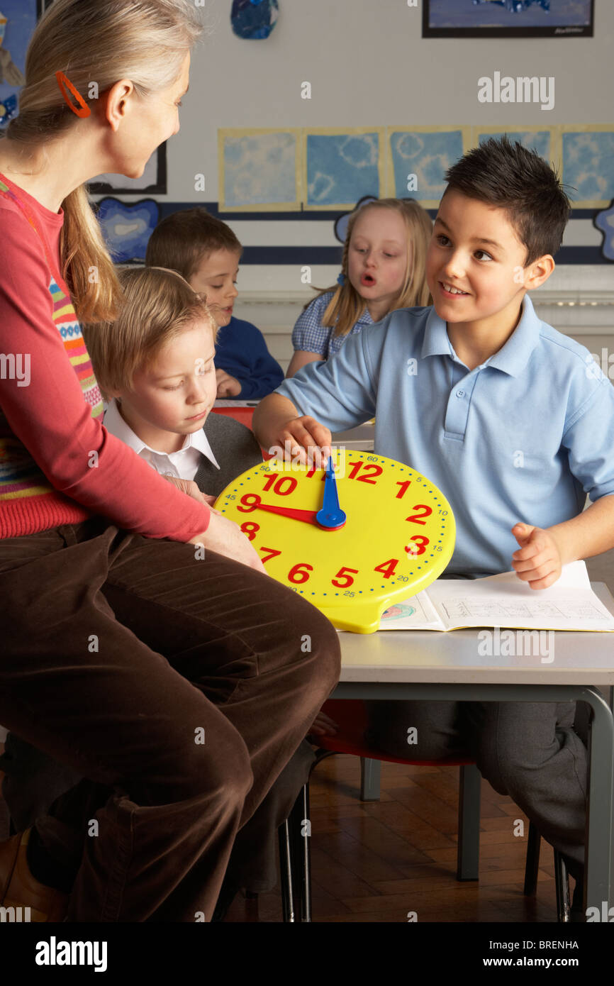 Lehrerin In der Grundschule unterrichten von Kindern im Klassenzimmer Uhrablesen Stockfoto