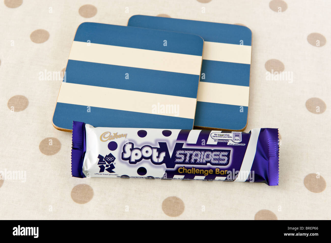 Cadbury Flecken und Streifen Choc-Bar und 2 Blau-Creme gestreiften Untersetzer auf einer Creme und braun gefleckten Matte Stockfoto