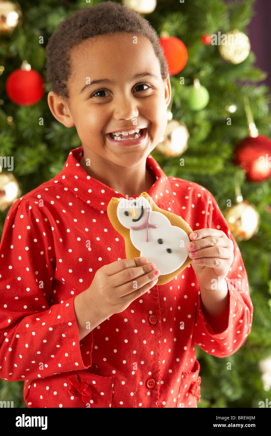 Kleiner Junge Cookie vor Weihnachten Baum essen Stockfoto