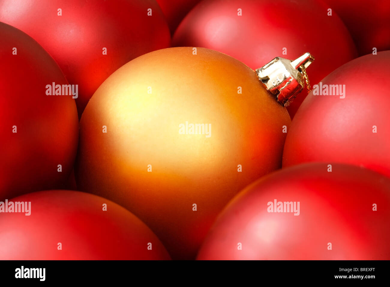 Goldene Weihnachtskugel, umgeben von roten Ornamenten Stockfoto