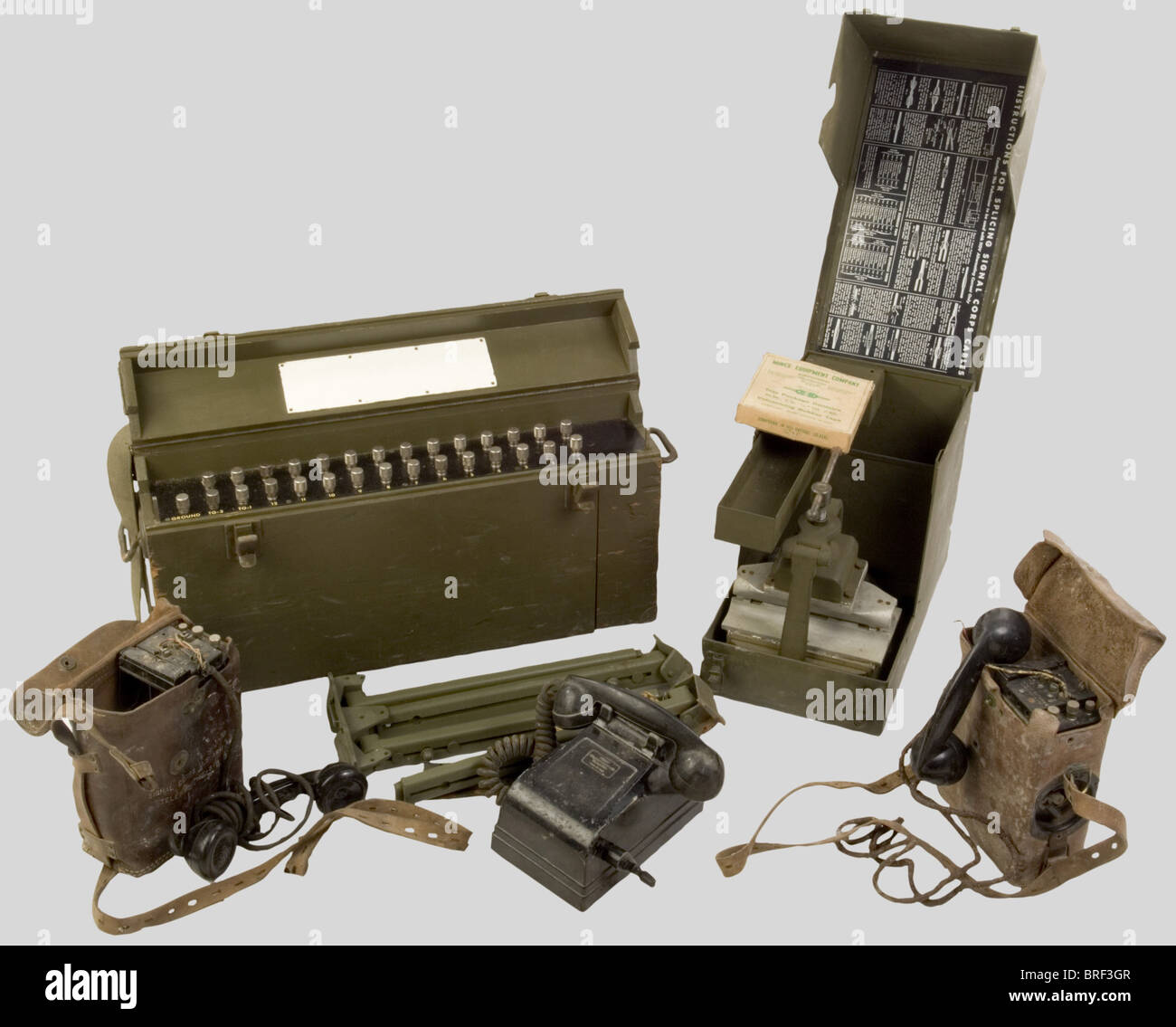 Etats Unis Deuxième Guerre Mondiale, Lot de matériel de téléphonie US Army, comprenant un Central téléphonique de campagne dans sa caisse en bois vert, modèle à douze lignes, câblage abwesend. Trépied de caisse complet dans sa boîte de dotation en carton. Atelier de Campagne pour Réparation de câblage téléphonique, dans sa caisse en métal vert comportant ses accessoires dont un étau de serrage. Plaques de Dotation du 'Signal-Korps-Kabel'. Deux téléphones de campagne dans leurs sacoches de Transport en cuir, boitiers métalliques et combinés présent, mais matériel, Stockfoto
