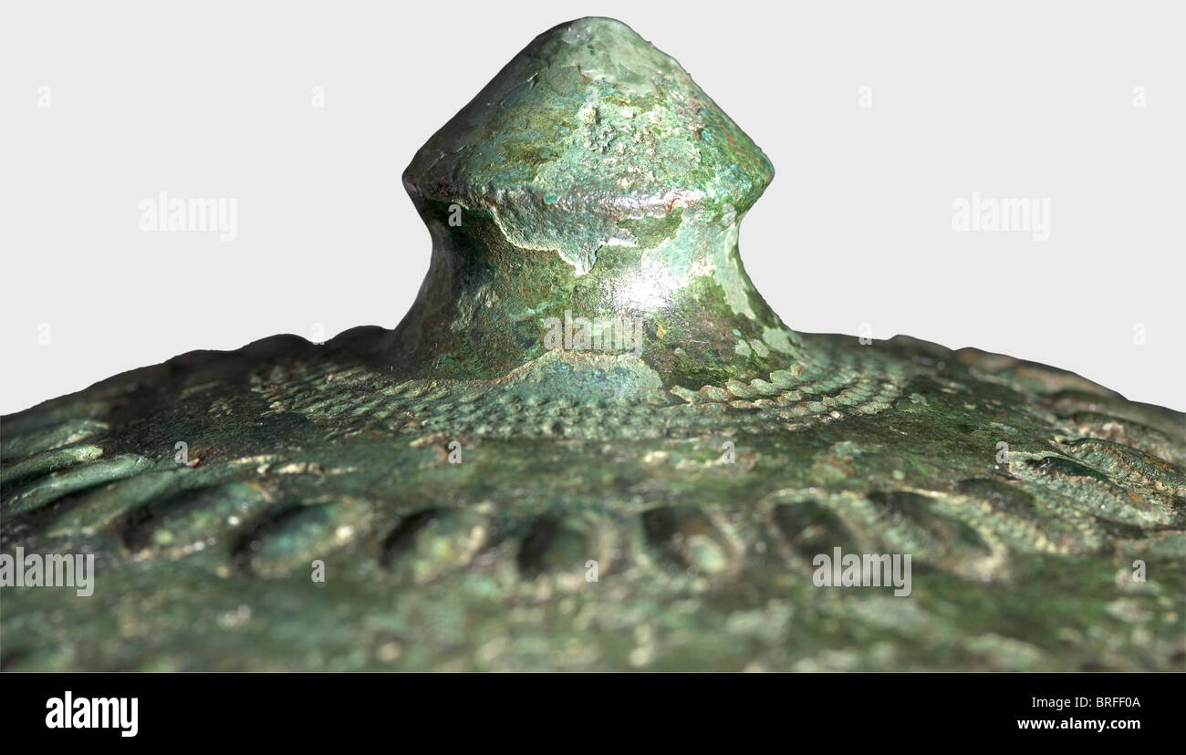 Ein nordwestiranischer dekorierter Schild, 1. Hälfte des 1. Jahrtausends vor Christus, EIN konischer Schild aus einem Stück Blechbronze, mit einem schweren, fusionsverschweißten, konischen Bumbo. Konzentrische Zierkreise aus eingeprägten und verkämmelten Dreiecken, Ringen, Punkten, länglichen Beulen und Serpentinlinien. Vier Lochpaare. Durchmesser 39,5 cm. Gewicht 562 g. Erhalten als Bruchstücke mit einer schönen grünen bis blaugrünen Patina. Der Schild gehört zu einer bekannten Gruppe üppig und meisterhaft gefertigter Zierschilde. Ähnliche Stücke aus der Sammlung Axel Guttmann finden Sie unter, Stockfoto