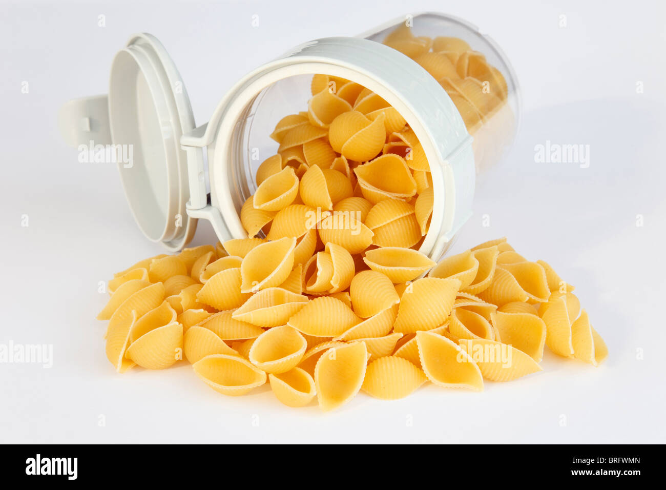 Haufen von rohem Conchiglie Pasta Muscheln aus einem Kunststoff-Lebensmittel-Behälter mit Deckel öffnen Stockfoto