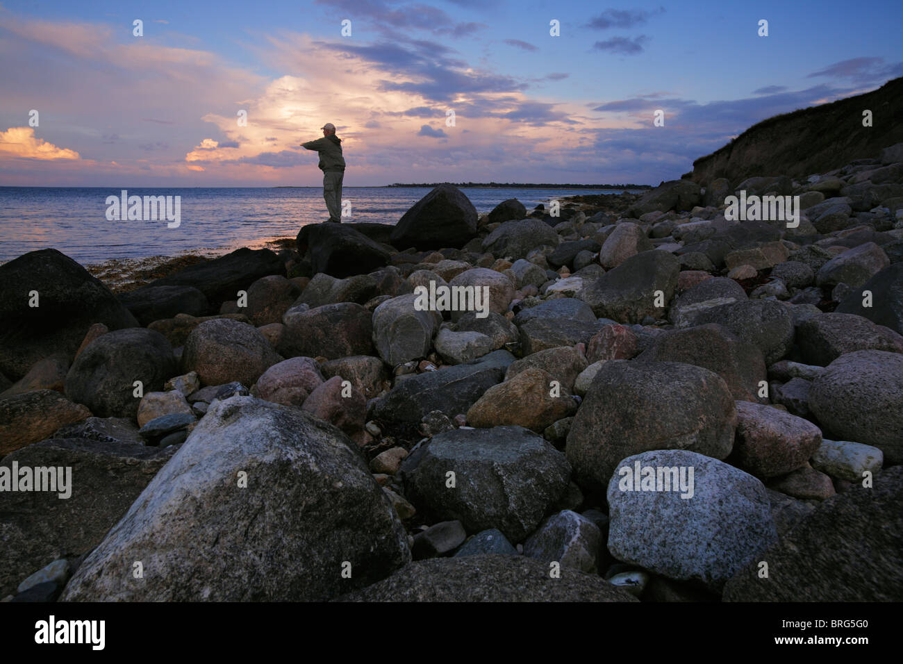 Mann, die Fischerei auf Meerforellen an der Fyn Gearkasse Ostsee in der Abenddämmerung Küste Stockfoto