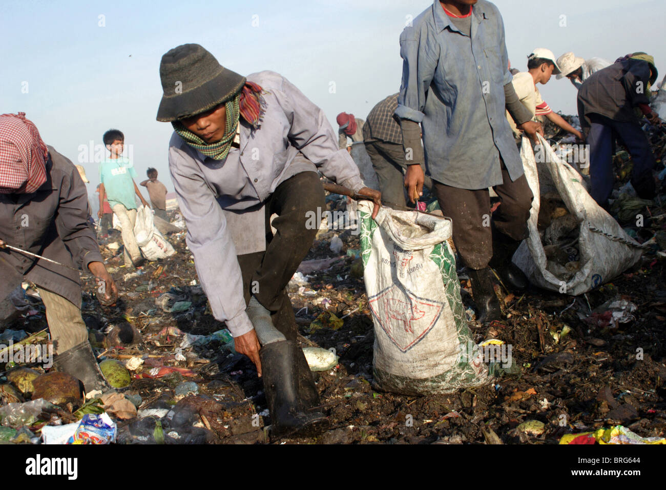 Eine Arbeitskraft bei Stung Meanchey Mülldeponie in Phnom Penh, Kambodscha, nimmt Müll aus ihrem Arbeitsstiefel. Stockfoto