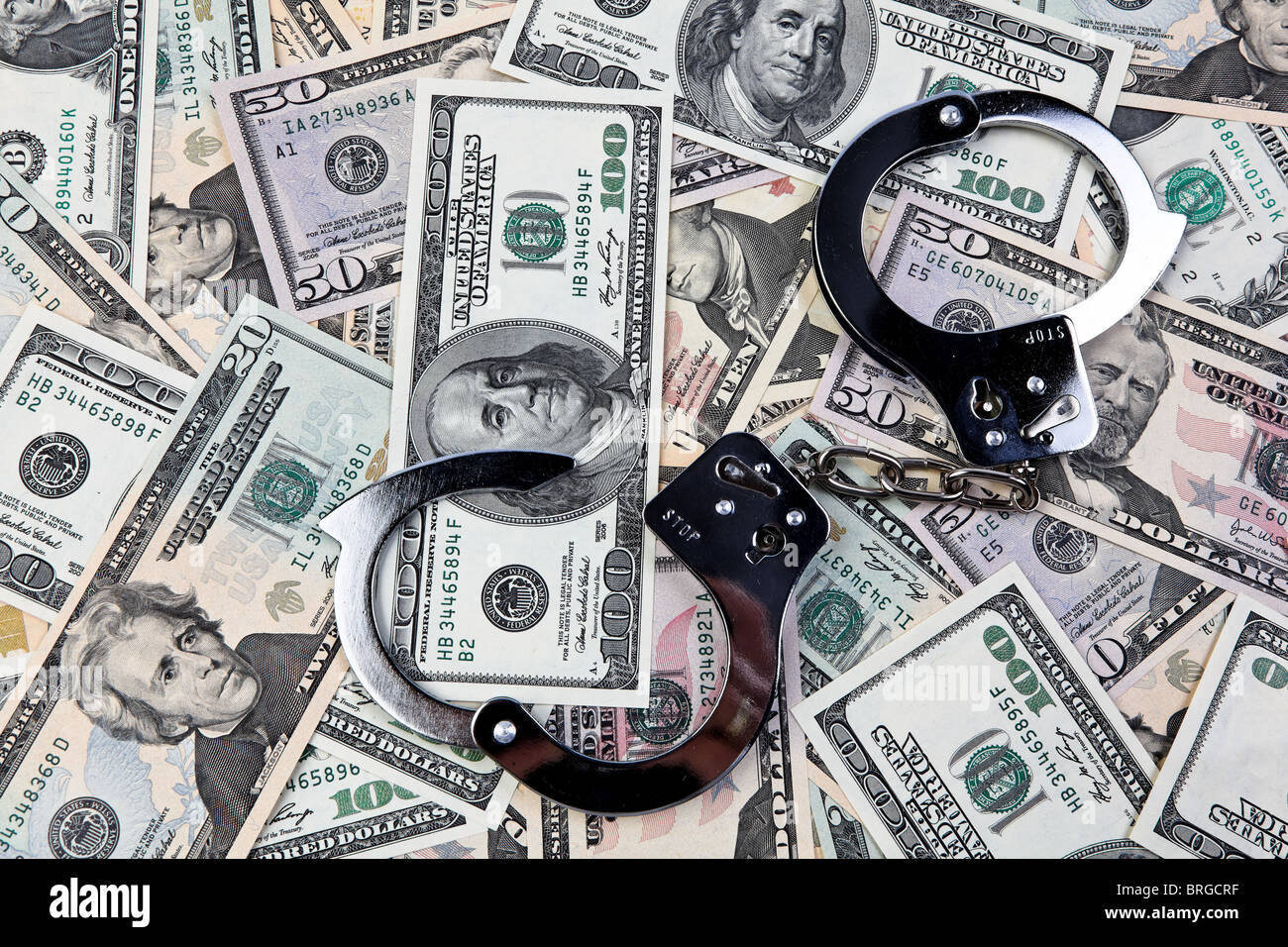 Symbol der Wirtschaftskriminalität. US-Dollar-Banknoten und Handschellen. Stockfoto