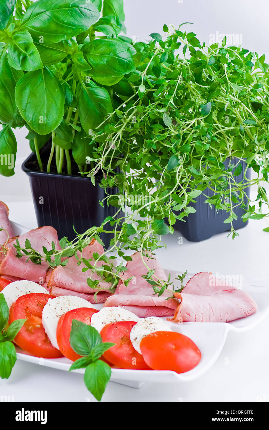 Teller mit Schinken, Tomate und Mozzarella mit Thymian und Basilikum Stockfoto