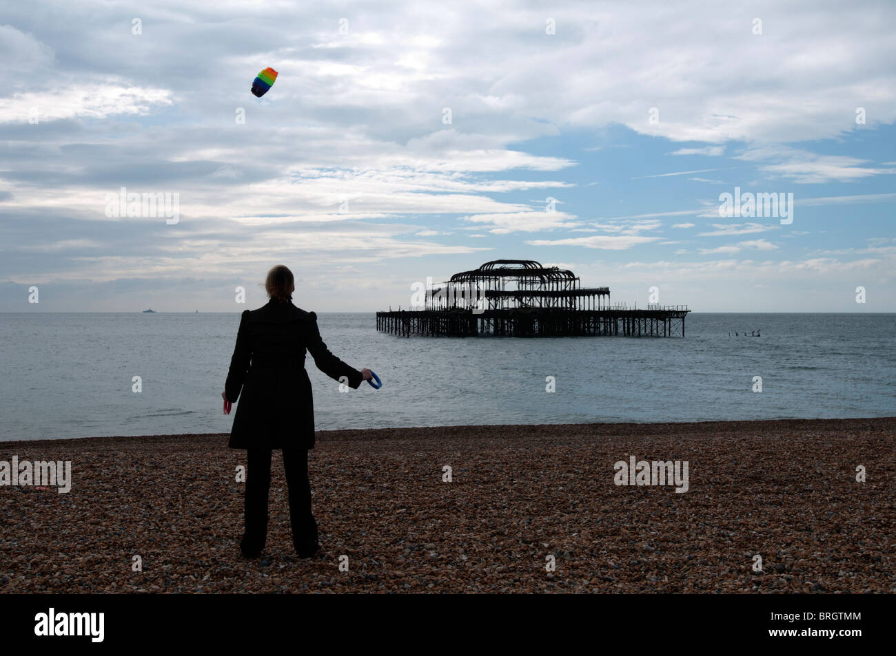 BRIGHTON, ENGLAND, 26. September 2010 - fliegt eine Frau einen Drachen auf der Strandpromenade in der Nähe der Überreste der West Pier. Stockfoto