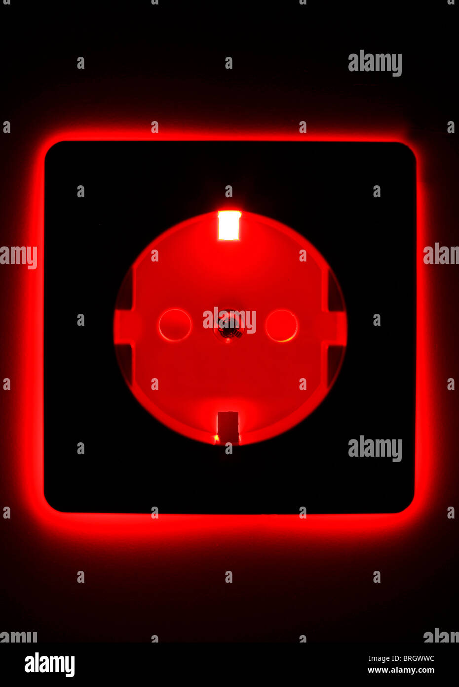 Steckdose in der Wand, beleuchtet, Energie-Symbol. Stockfoto