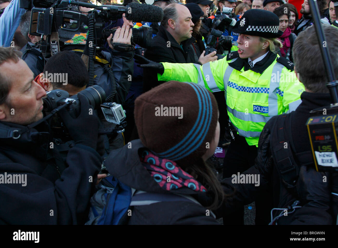 Presse und Medien umgeben ein einsamer Polizei Polizistin bei einer London-Demo. Stockfoto