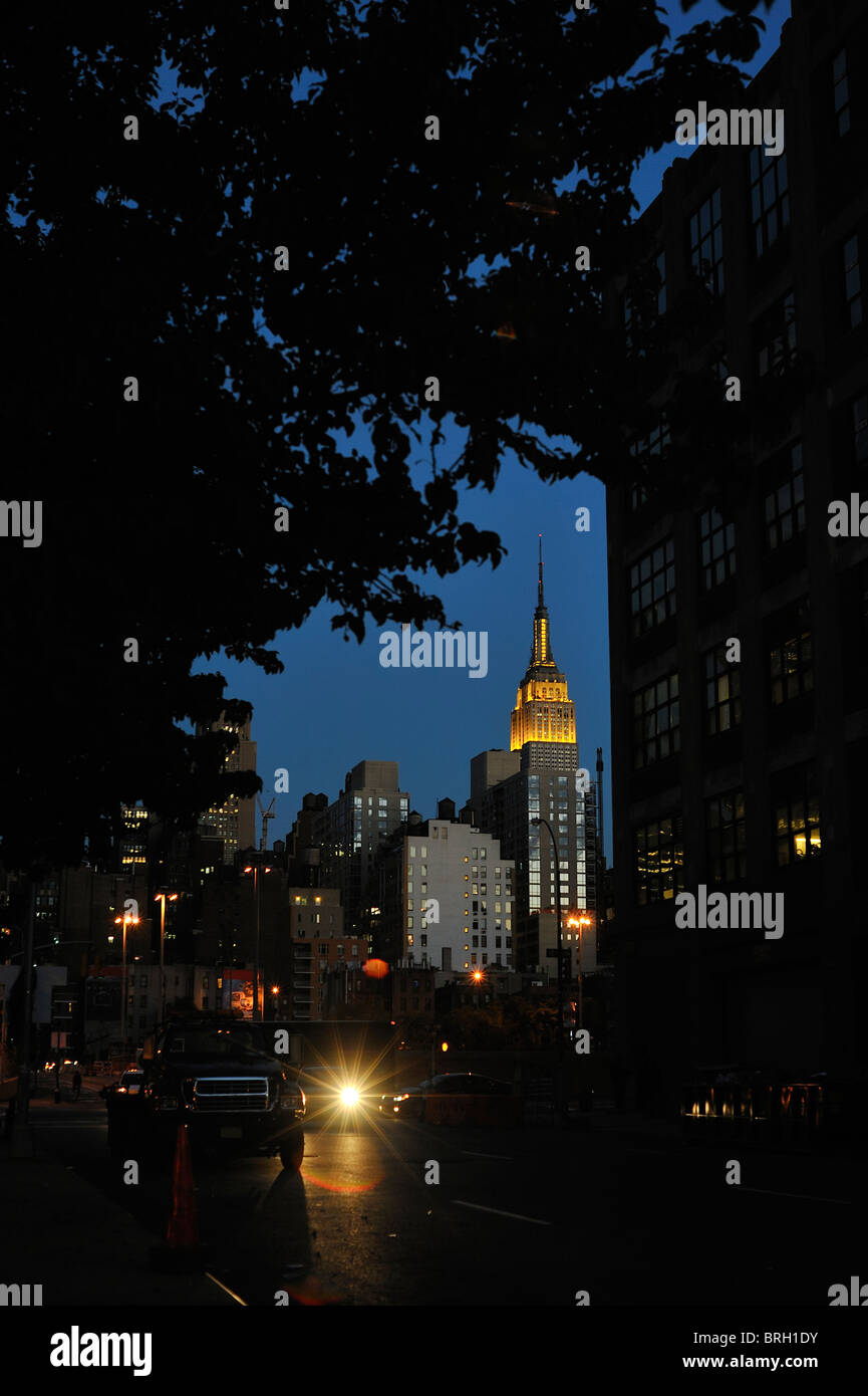 New Yorker Wahrzeichen der Empire State Building gold Lichter oben und Spire nachts beleuchtet gesehen, umrahmt von Bäumen New York City. Stockfoto