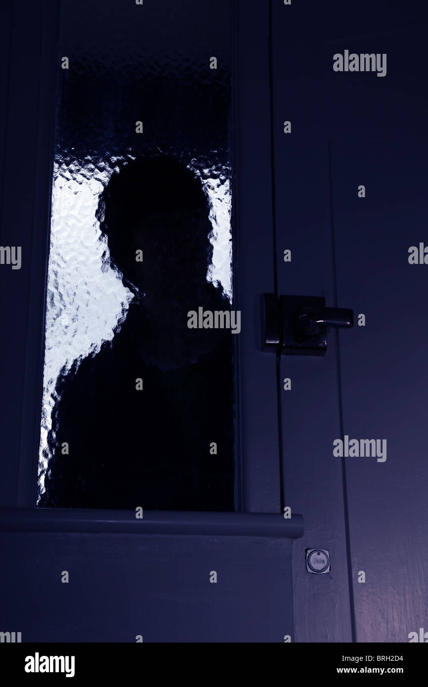 Silhouette männlichen Eindringling Blick durch eine undurchsichtige Fenster neben einer Haustür Stockfoto