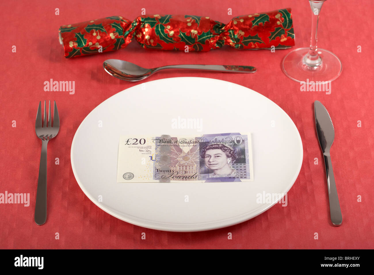 zwanzig Pfund Banknote auf einem weißen Teller auf roten Tischdecke Gedeck und Christmas cracker Stockfoto