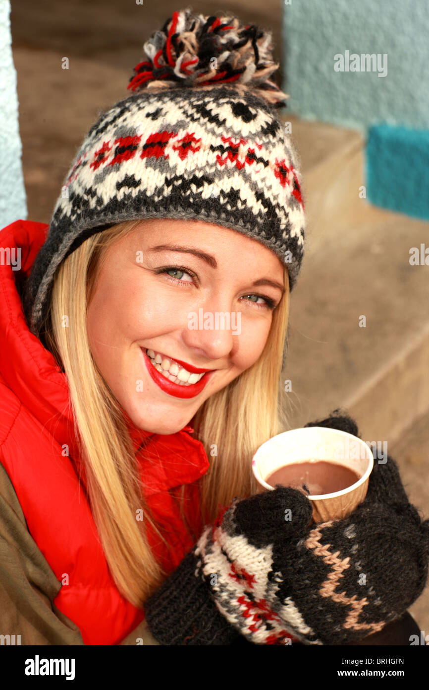 Junge Frau verkleidet die bittere Kälte im Winter Trinken einer Tasse Kaffee zum Mitnehmen zu kämpfen Stockfoto