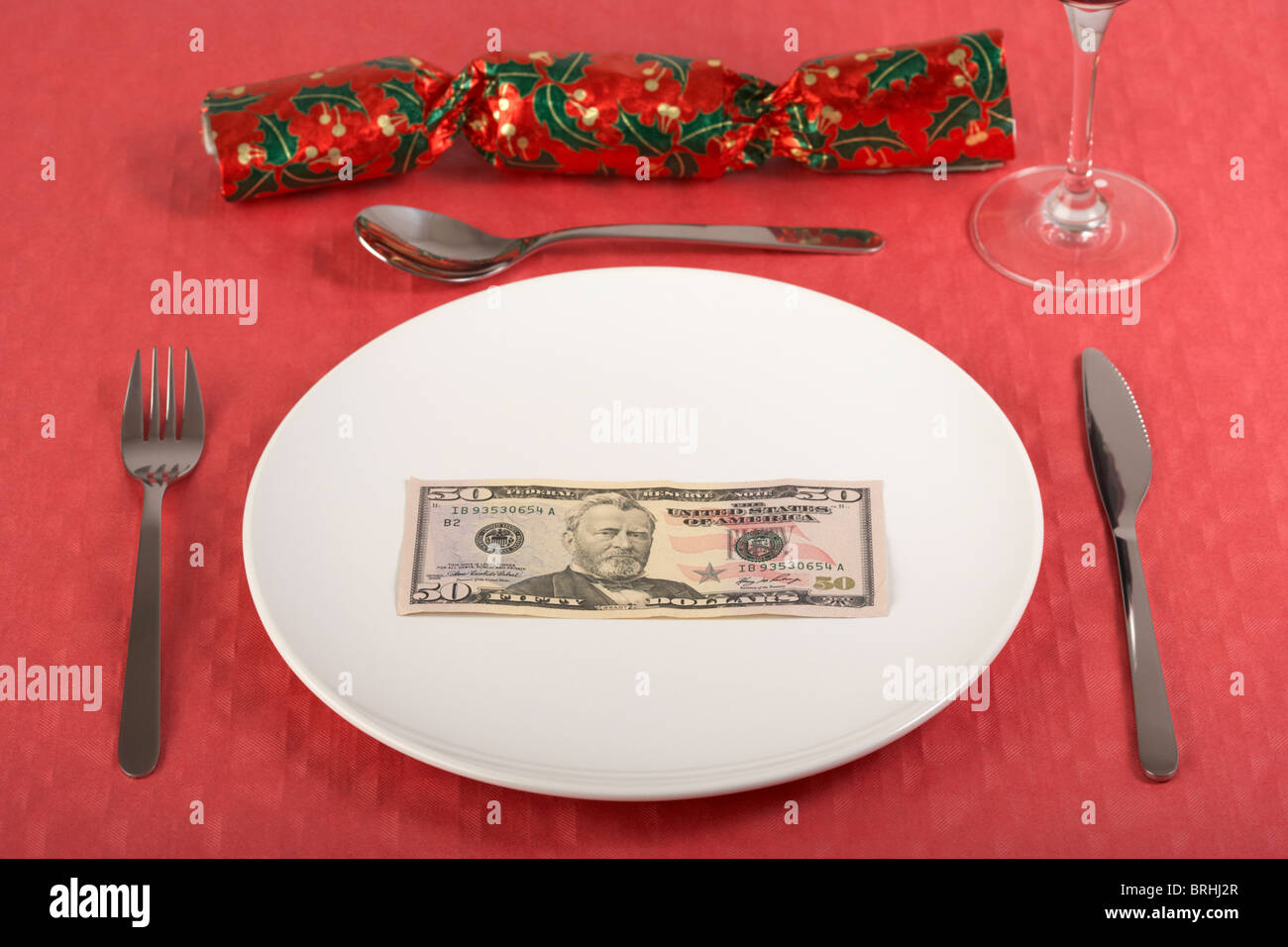 fünfzig-Dollar-Banknote auf einem weißen Teller auf roten Tischdecke Gedeck und Christmas cracker Stockfoto