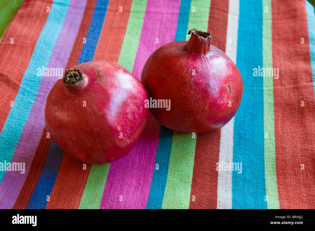 Granatapfel Früchte mit einem bunt gestreiften Baumwolle Tuch Hintergrund. Stockfoto